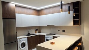 A modern kitchen with a central island, built-in appliances, and pendant lighting. - Dahan Sirena lighthouse luxury apartment (Paphos)