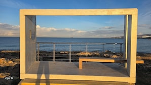 A concrete structure with a metal railing overlooking a rocky shoreline and the sea. - Dahan Sirena lighthouse luxury apartment (Paphos)