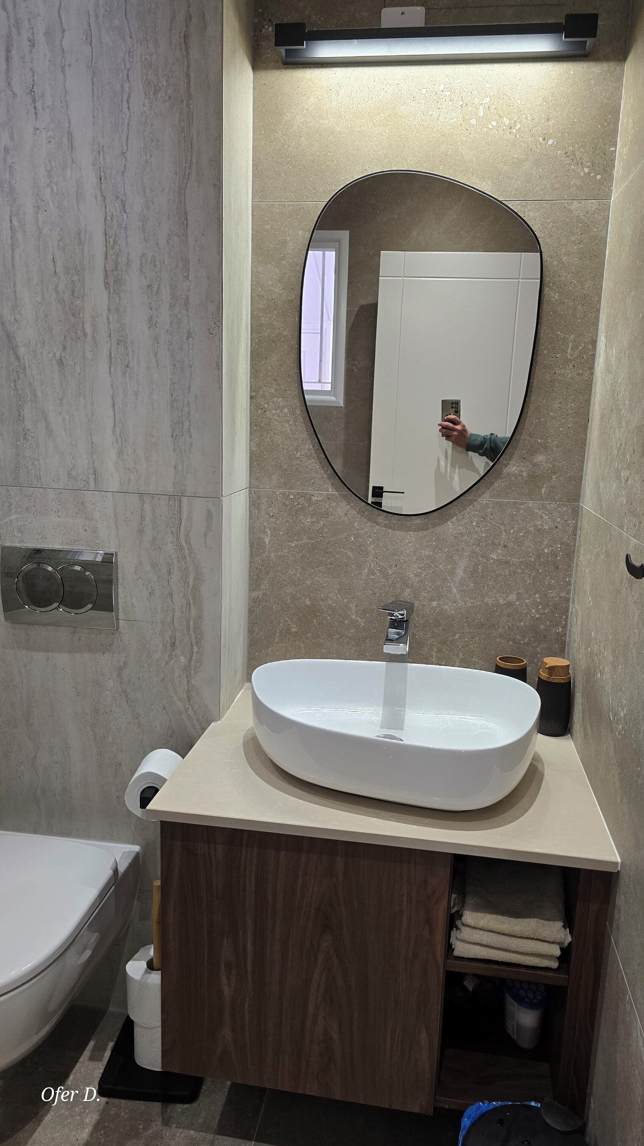 Een badkamer met een witte wastafel, een spiegel en een toilet.