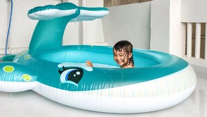 A child in a blue and white inflatable pool with a whale design, featuring a water spout and a whale face. - Warayunso Villa (Naha)