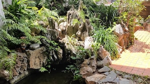 A rock garden with a water feature, surrounded by various plants and ferns. - Warayunso Villa (Naha)
