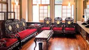 A traditional room with ornate wooden furniture, a wooden floor, and large windows with decorative glass panes. - Warayunso Villa (Naha)