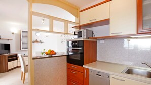 Une cuisine moderne avec des meubles en bois, un four encastré, un four à micro-ondes et un lave-vaisselle.