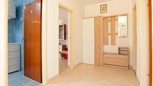 Un couloir avec une porte en bois donnant accès à une salle de bain, un placard et un miroir.