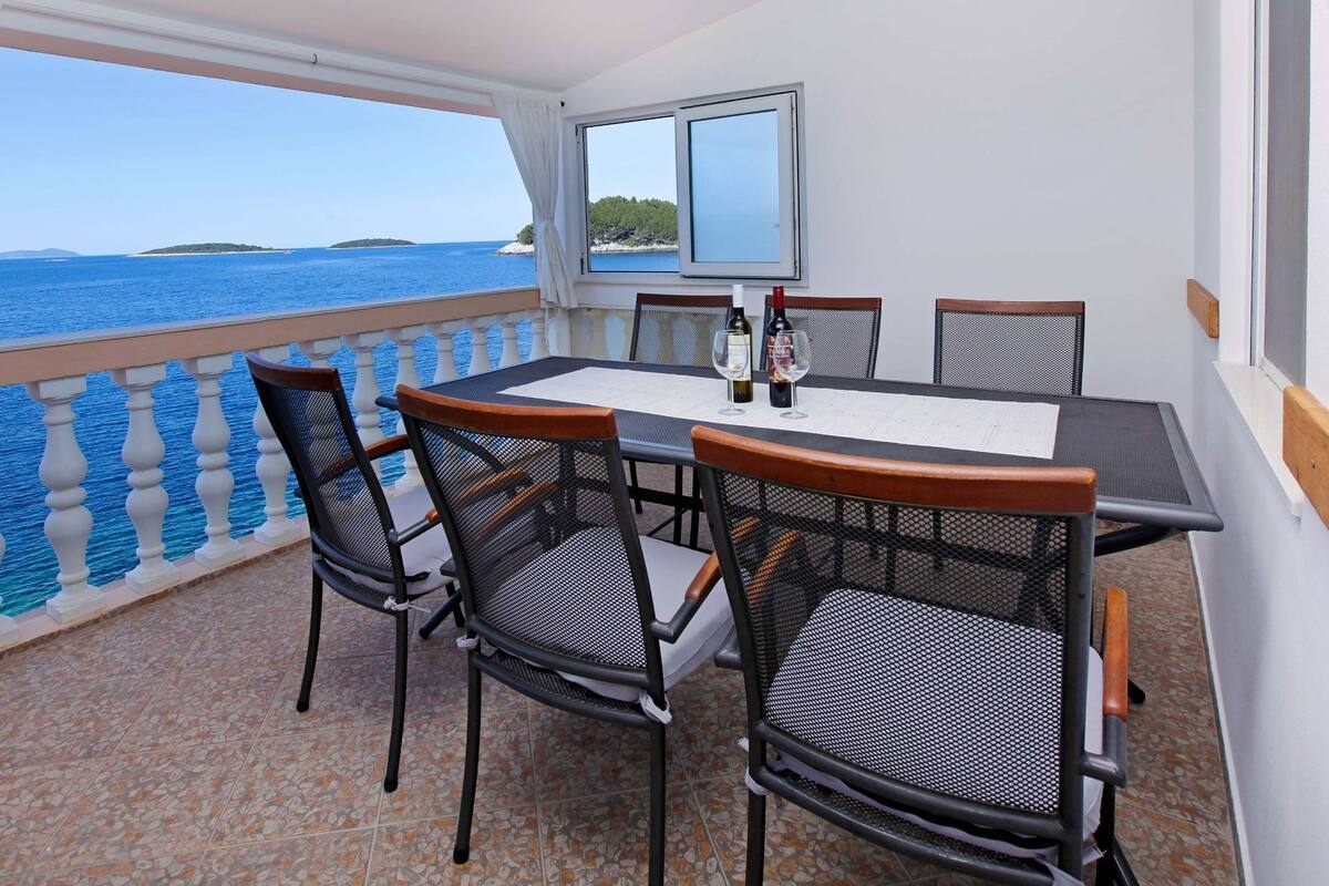 Un balcón con mesa y sillas, con vistas al mar.