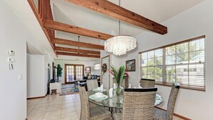 A dining area with a glass table, wicker chairs, and a chandelier.