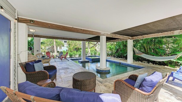 A covered outdoor area with wicker furniture, a pool, and a hammock.