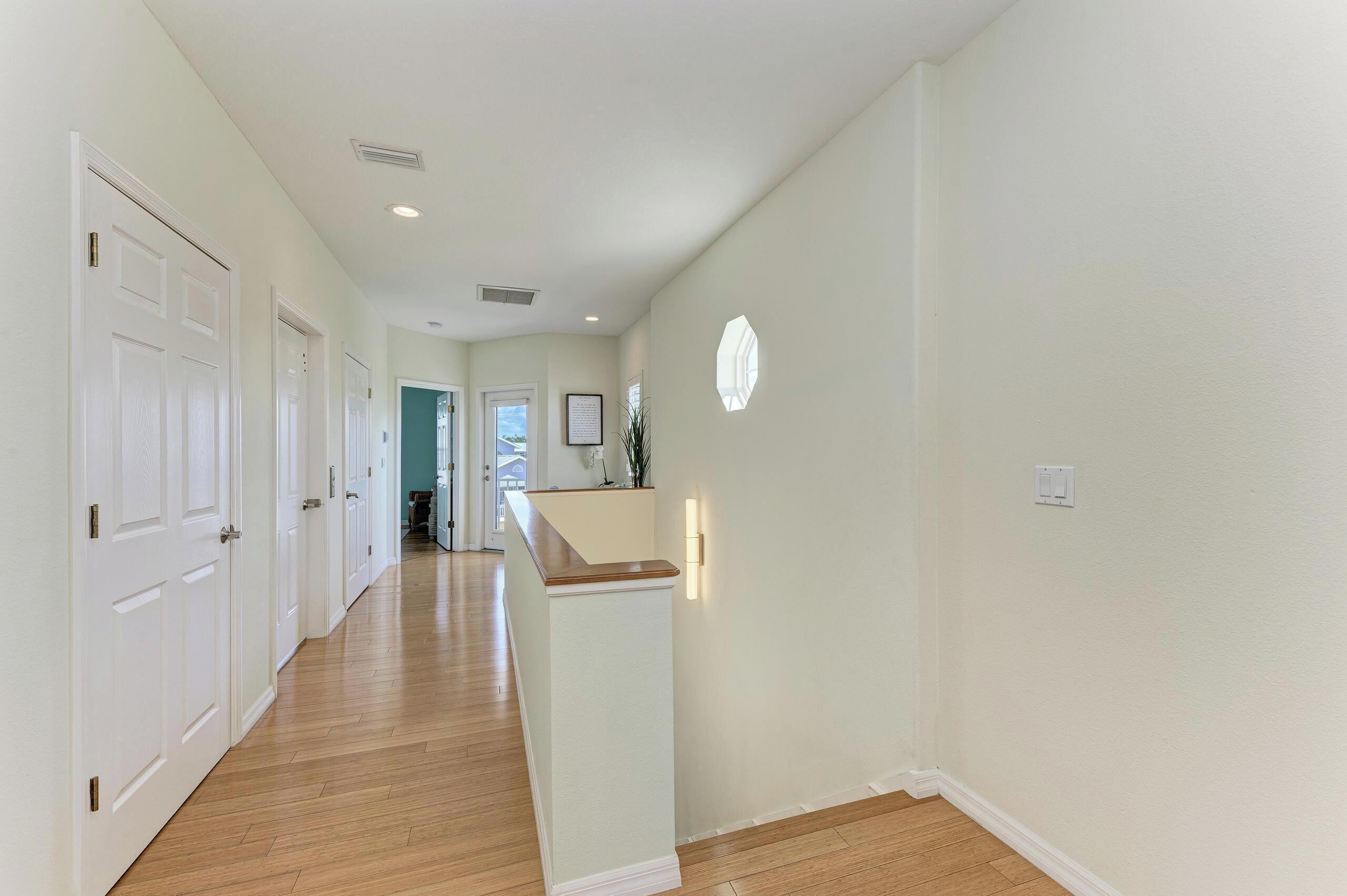 A hallway with wooden flooring, white walls, and a white door at the end.