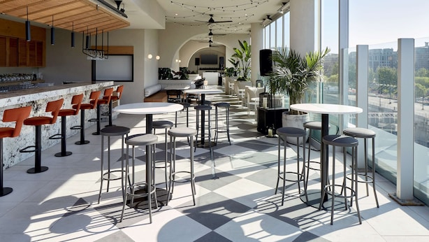 A modern bar area with high stools, a counter, and a view of the city.