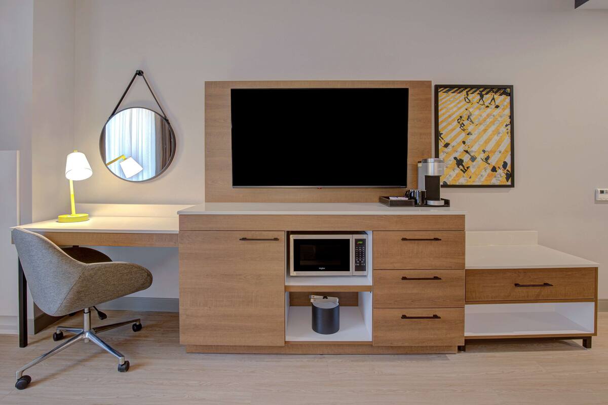 A modern bedroom with a bed, bedside table, and a large window.