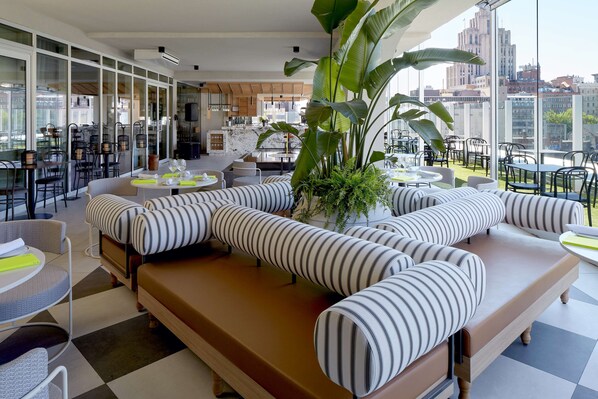 A modern lounge area with a large sectional sofa, a dining table, and chairs.