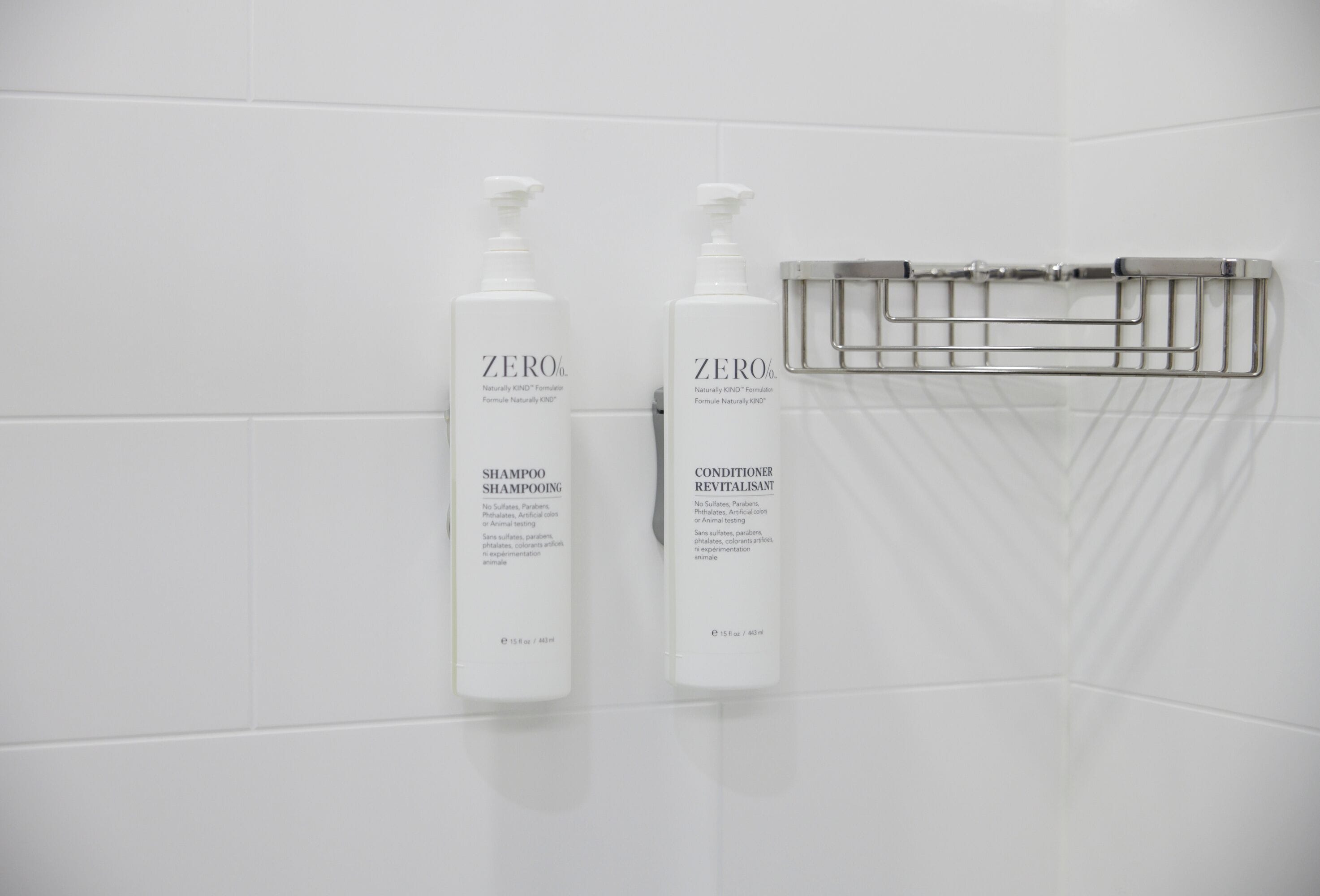 Duas embalagens de shampoo e condicionador ZERO sobre um revestimento de azulejos brancos.