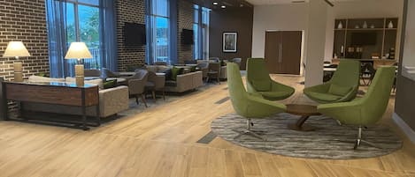 A spacious lobby with a brick wall, large windows, and a modern ceiling fan.