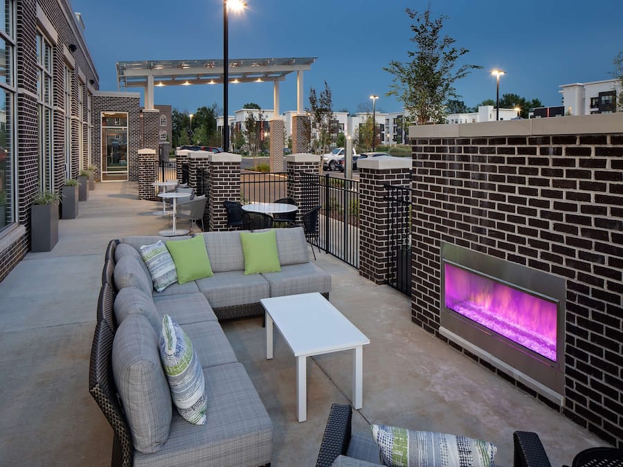 An outdoor patio area with a sectional sofa, a small table, and a built-in fireplace.
