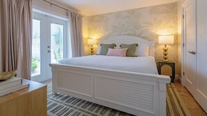 Een slaapkamer met een bed, twee bedlampen, een deur en een raam met gordijnen.