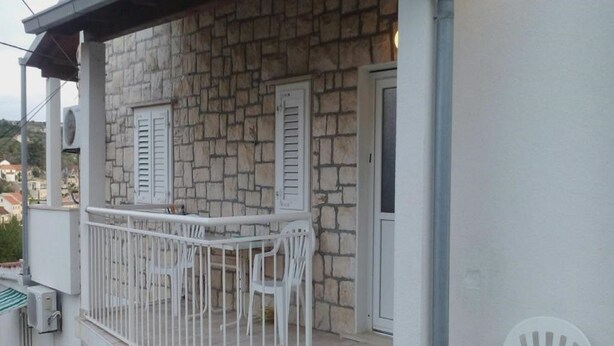 A stone building with a balcony, white shutters, and a white chair. - Apartment Agata (Supetar)