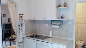 A compact kitchen with white cabinets, a built-in dishwasher, a sink, and a small countertop. - Apartment Agata (Supetar)