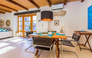 A dining area with a wooden table, black chairs, and a hanging pendant light.
