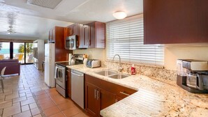 Una cocina con gabinetes de madera, encimera de granito, microondas, tostadora y cafetera.