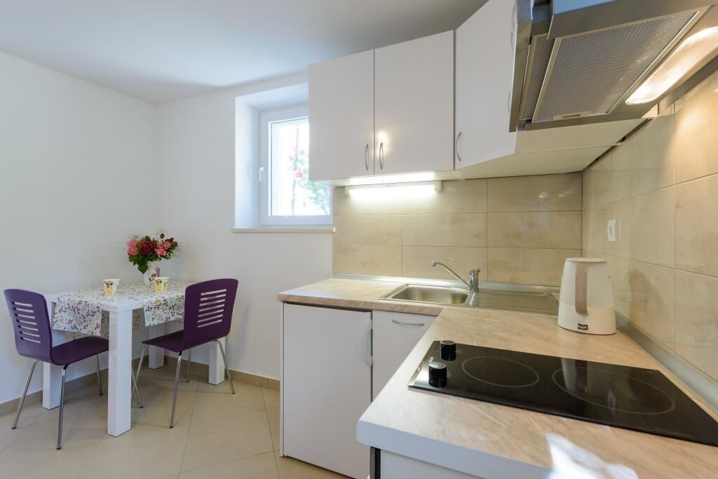 A compact kitchen with a small dining area, a built-in oven, and a window providing natural light.