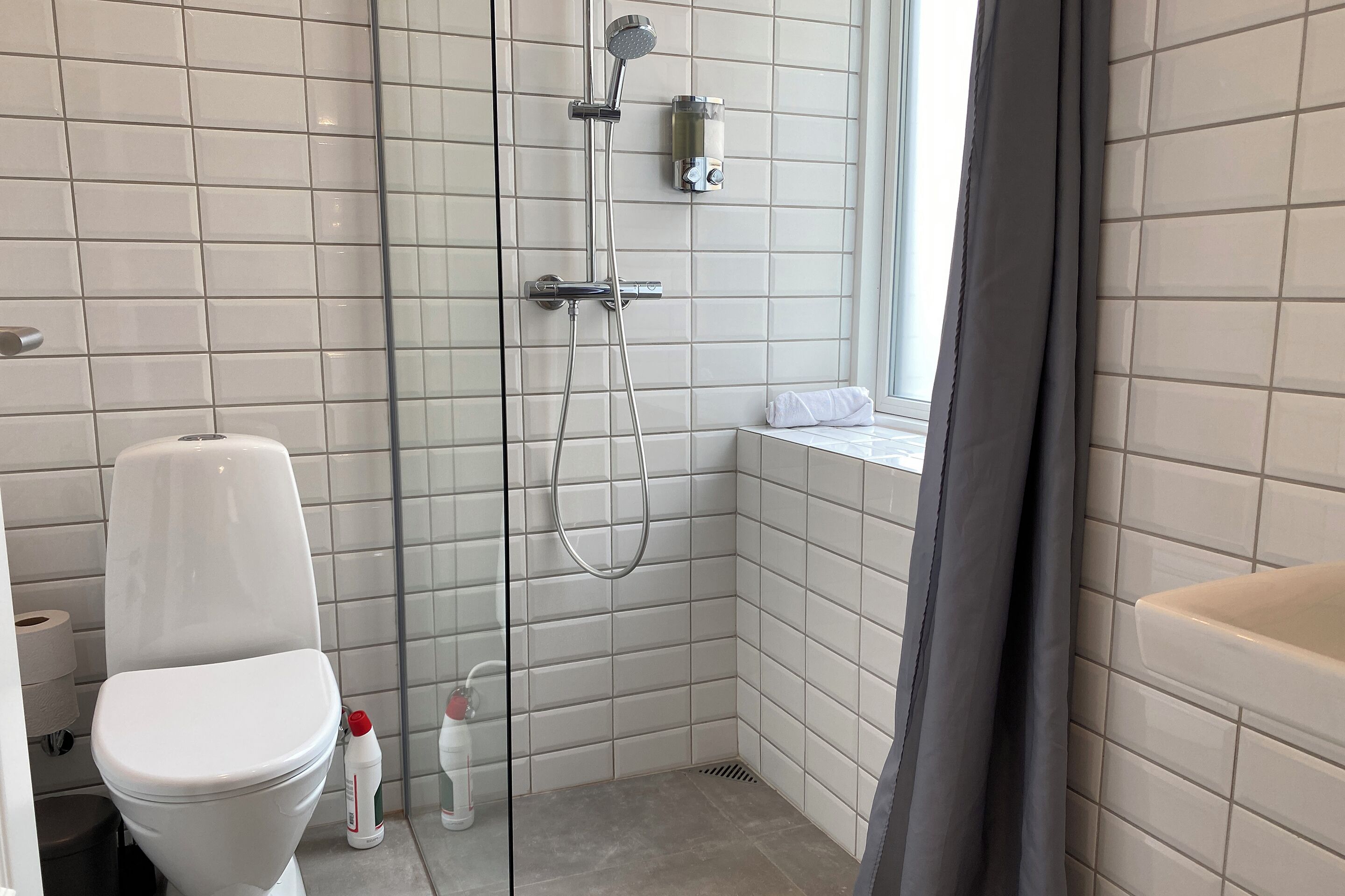 A modern bathroom with a glass-enclosed shower, a toilet, and a sink.