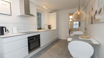 A modern kitchen with white cabinetry, a built-in oven, and a coffee maker.