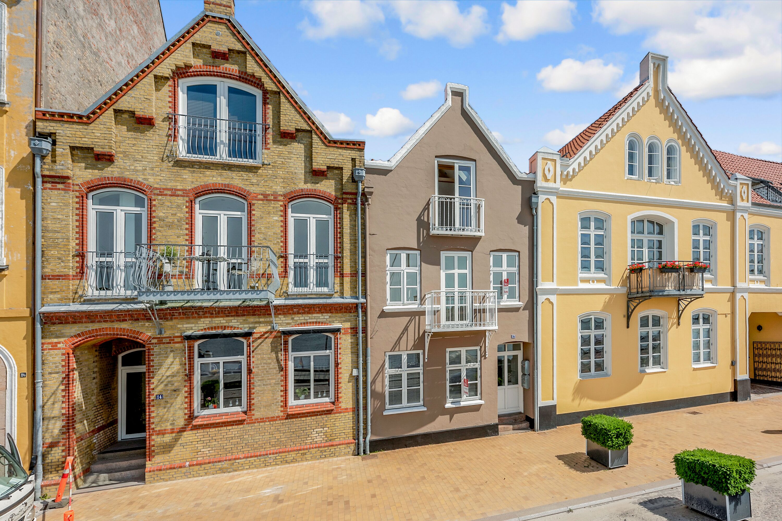 Eine Reihe von dreigeschossigen Gebäuden mit unterschiedlichen Architekturstilen, inklusive Balkonen und großen Fenstern.