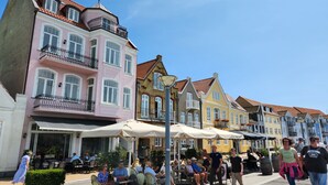 Une rangée de bâtiments aux couleurs vives, dotés d’espaces extérieurs aménagés pour s’asseoir et d’un chemin piétonnier.