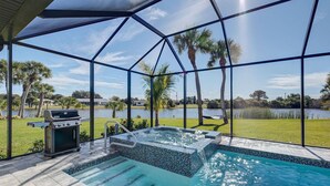 Ein Poolbereich mit Whirlpool, Grill und Blick auf einen See sowie Palmen.