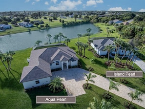 Zona residencial con casas llamadas Aqua Pearl e Island Pearl, con un lago y céspedes bien cuidados.