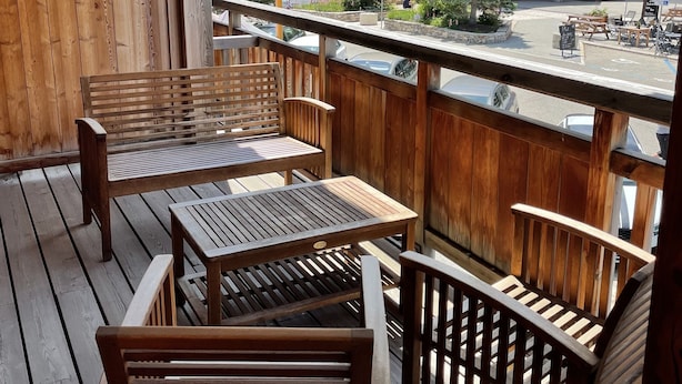 Eine Holzdachterrasse mit Sitzgelegenheiten, mit Blick auf eine Stadt, Gebäude und einen Berg im Hintergrund.
