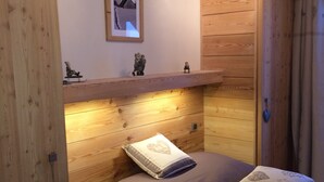 Ein gemütliches Schlafzimmer mit einem hölzernen Kopfteil, einem Bett mit zwei Kissen, einem Regal mit Dekoration und einem gerahmten Bild an der Wand.