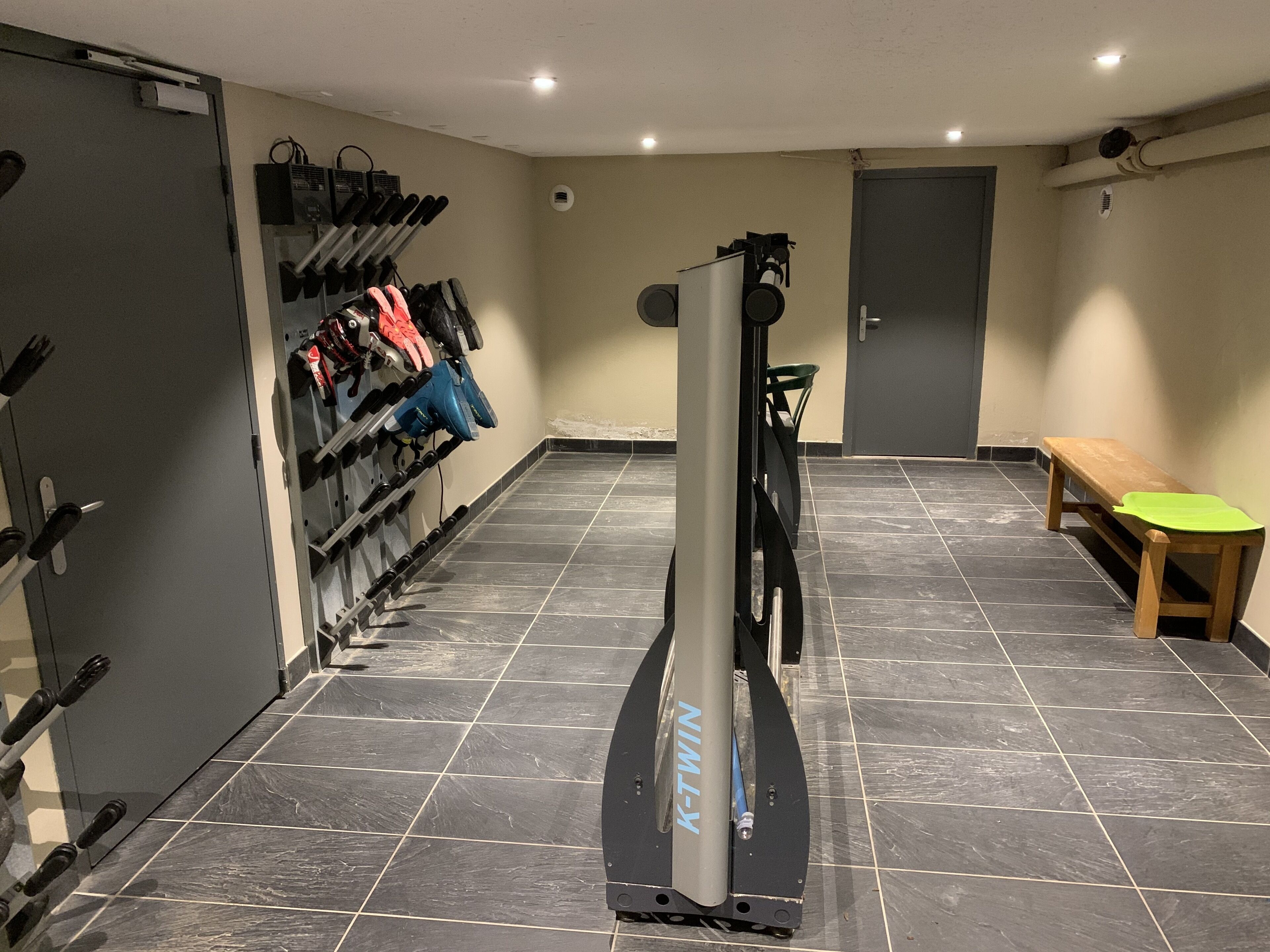 A gym with exercise equipment, a bench, and a door.