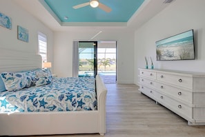 Un dormitorio con cama, cómoda, ventilador de techo y un cuadro.