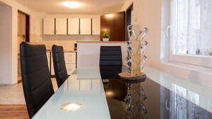 A modern dining area with a glass table, black chairs, and a decorative glass sculpture. - Holiday home Veki (Korenica)