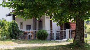 A building with a gated entrance, a small garden area, and a tree in the foreground. - Holiday home Veki (Korenica)