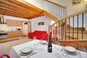 A dining area with a table set for a meal, a bottle of champagne, and a red chair. - Lagoon Apartment (Venezia)
