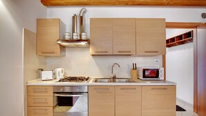 Une cuisine moderne dotée d’armoires en bois, d’appareils électroménagers en acier inoxydable, d’un four à micro-ondes et d’un four encastré.