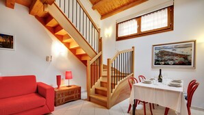 Un coin repas avec un escalier en bois, un canapé rouge et une table mise pour le dîner.