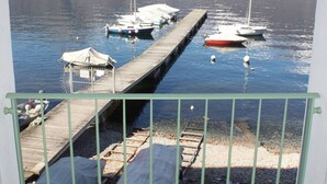 A marina with boats docked, a wooden pier, and mountains in the background. - The Green House on the Lake (Lezzeno)