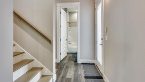 A hallway with a staircase, a door leading to a bathroom, and a doormat. - Home with rooftop beach views, winter open, snowbirds welcome! (Panama City Beach)