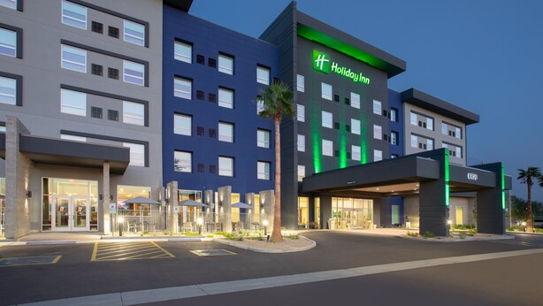 Un hotel Holiday Inn con fachada moderna, varios pisos y una entrada bien iluminada.