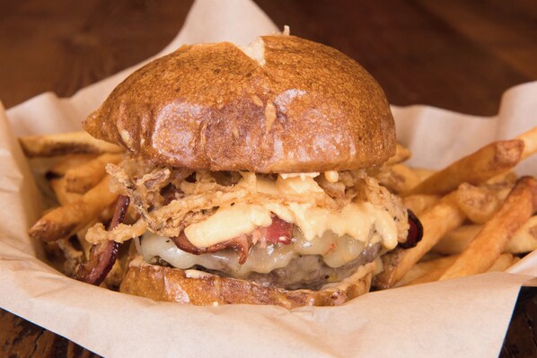 Un sandwich composé d’un pain, de fromage et de viande, servi avec des frites.