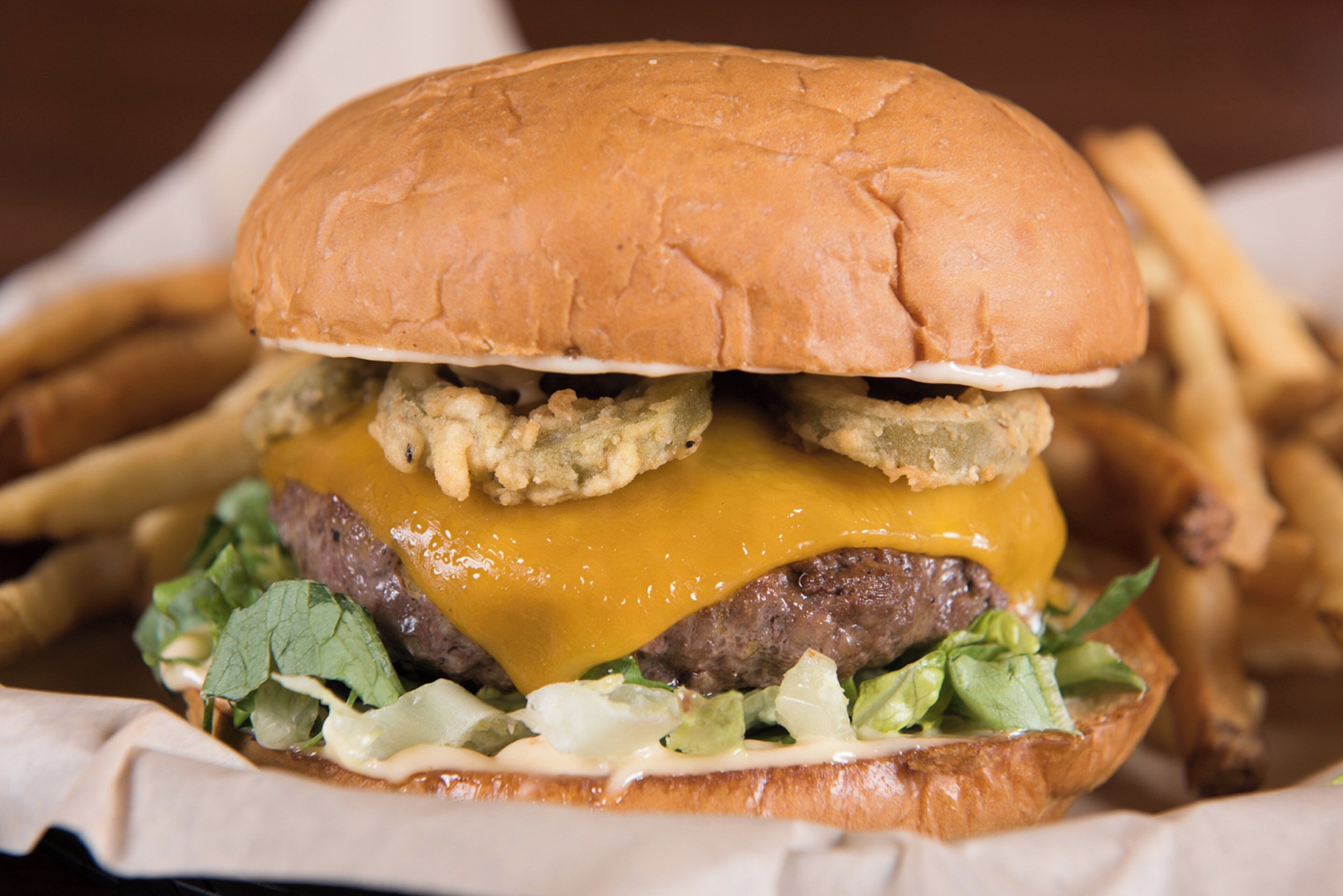 Una hamburguesa con pan, queso, lechuga y una carne.