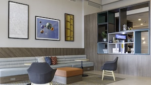 A modern lobby with a grey sofa, two armchairs, a coffee table, and a large window with shelves.