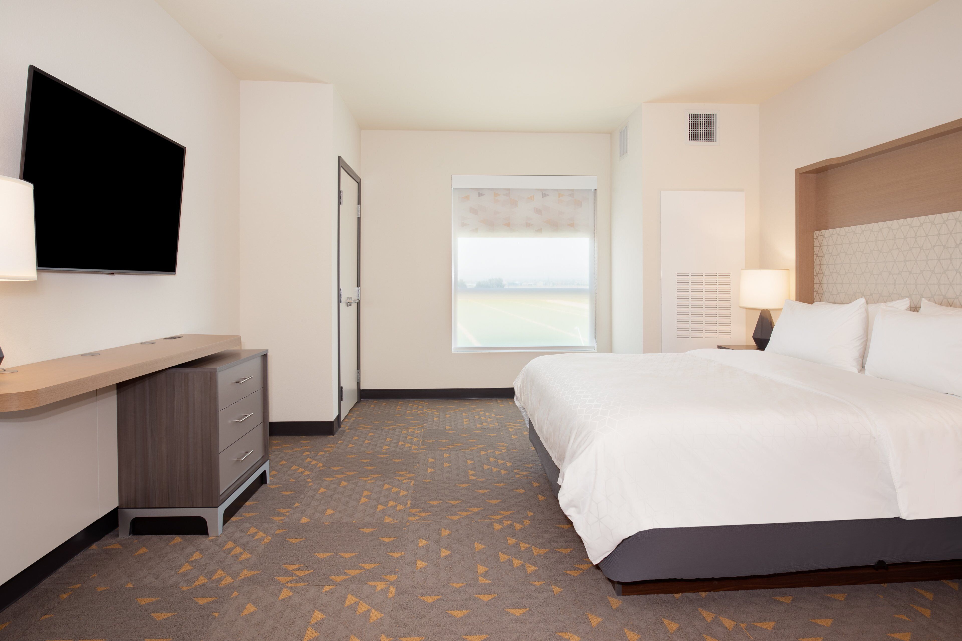 A hotel room with a bed, a desk, a television, and a window with a view.