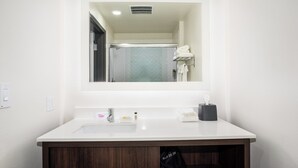 A modern bathroom with a white sink, dark wooden vanity, and a mirror above the sink.