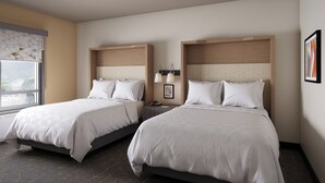 A hotel room with two beds, a window, a lamp, and a framed picture on the wall.