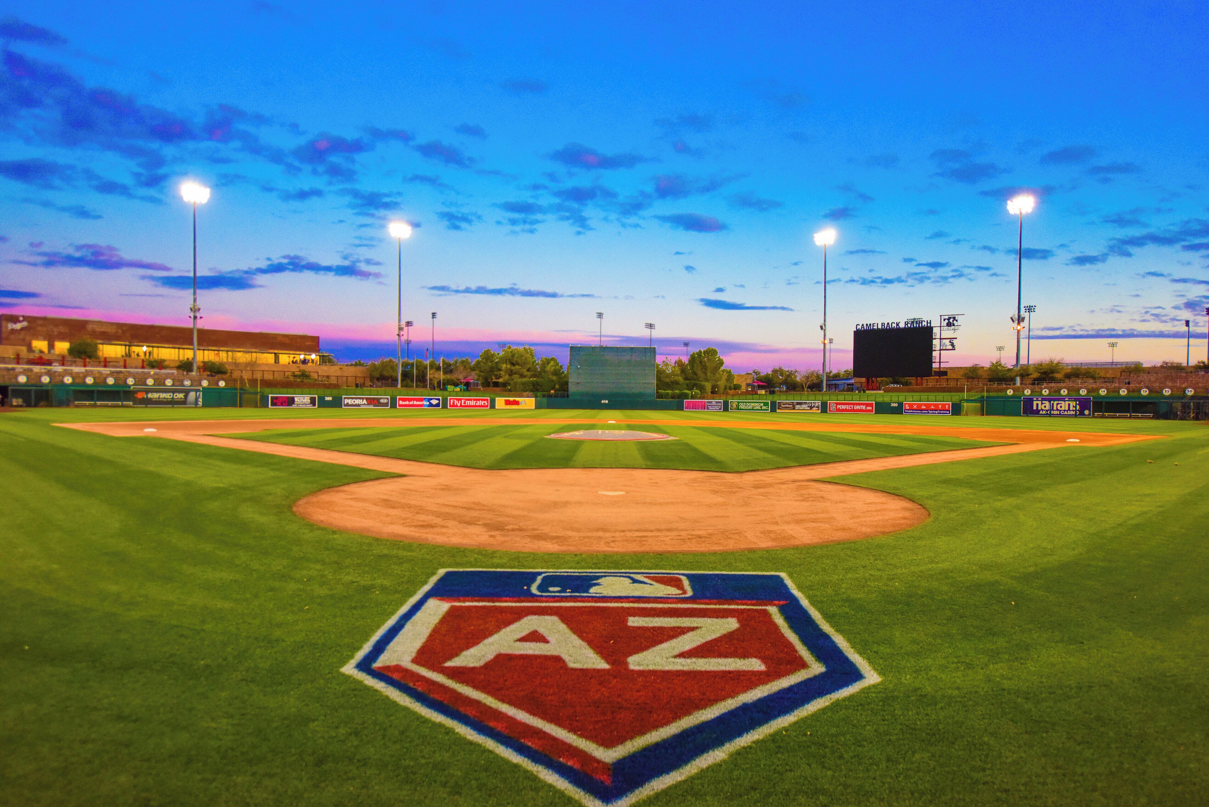 Un campo de béisbol con un gran logo de AZ en el centro, rodeado de publicidad y un marcador en el fondo.