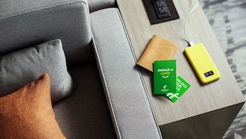 A modern hotel room with a grey sofa, a wooden side table, and a power strip.